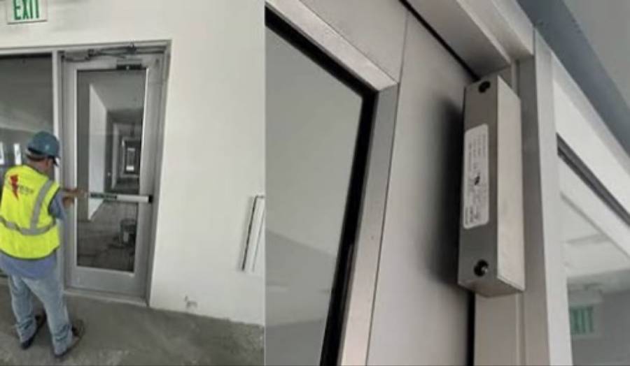 Installer fitting mag-lock hardware on a commercial door
